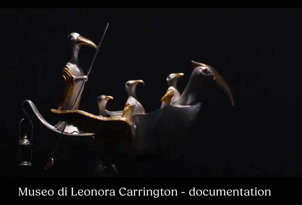 A silver sculpture of a bird-boat carrying other birds by surrealist Leonora Carrington against a black bacground, The title says Museo Di Leonora Carrington - documentation